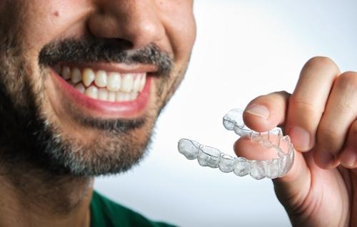 man holding his clear aligners in burke va