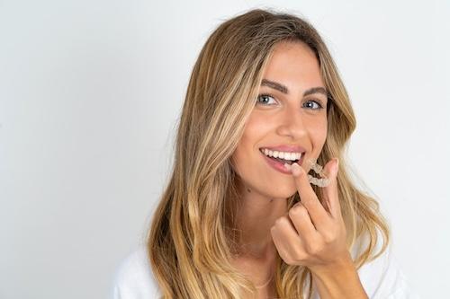 woman putting on her invisalign in burke va